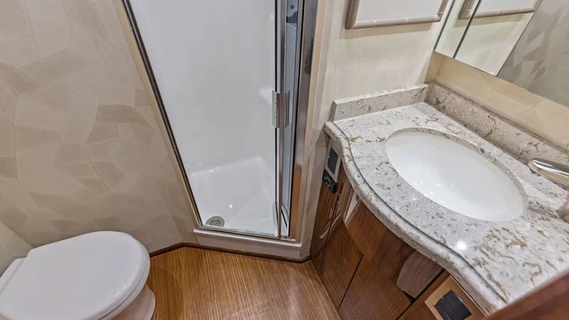 Slide: The Image of Elegant Yacht Bathroom with Shower This luxurious bathroom on the Viking 62 Enclosed Bridge features a sleek, modern design with a spacious shower. The elegant vanity is topped with a polished stone countertop, complemented by rich wood cabinetry, offering ample storage space. High-quality - 7751264