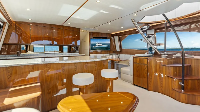 Slide: The Image of Luxurious Interior Salon This elegant salon in the 2018 Viking 62 Enclosed Bridge features high-gloss wood finishes and a spacious layout. The area includes a comfortable seating arrangement, a sleek bar with modern stools, and large windows offering panoramic views. The sophisti - 7751223