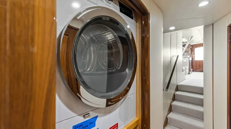 Slide: The Image of Hallway Laundry Area with Dryer This image showcases the convenient laundry area aboard the Viking 62 Enclosed Bridge. The modern dryer is elegantly integrated into the hallway, framed by warm wooden accents. The well-lit corridor leads towards the main living spaces, highlighting the v - 7751233