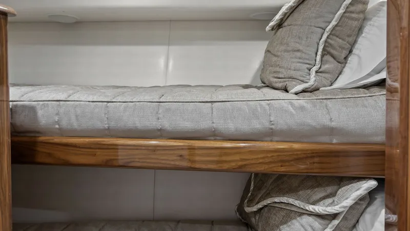 Slide: The Image of Cozy Bunk Cabin This image showcases the cozy bunk cabin aboard the 2018 Viking 62 Enclosed Bridge. The space features plush bedding with neutral tones, providing a comfortable retreat for guests. The craftsmanship of the wooden accents adds warmth and elegance to the sl - 7751261
