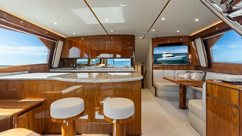 Slide: The Image of Elegant Salon with Open Seating The salon of the 2018 Viking 62 Enclosed Bridge exudes luxury with its polished wood finishes and expansive windows that offer panoramic ocean views. The spacious layout includes plush seating and a sleek, modern bar area, perfect for entertaining. Ambien - 7751216