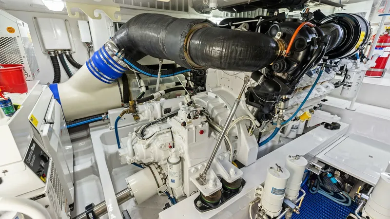 Slide: The Image of Engine Room with High-Performance Engine The engine room of the 2018 Viking 62 Enclosed Bridge, 'Joan's Boys,' showcases a meticulously maintained high-performance engine. The space is designed for efficiency, featuring organized piping and advanced filtration systems. The clean, white interior - 7751292