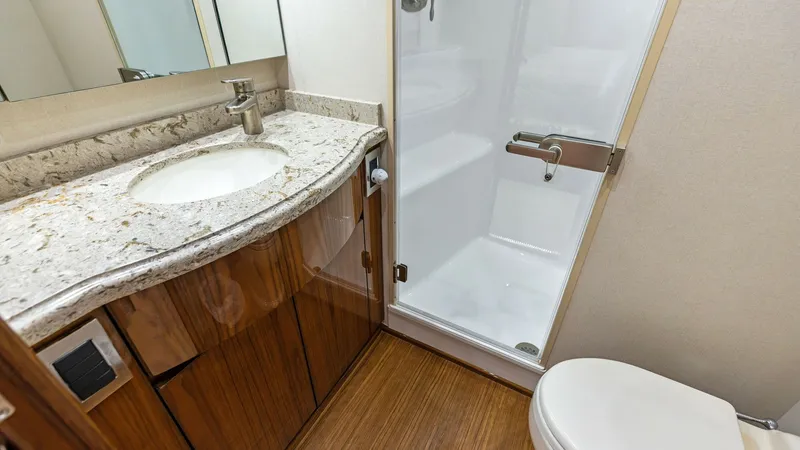 Slide: The Image of Elegant En Suite Bathroom This en suite bathroom features a sleek, modern design with a polished stone countertop and elegant wood cabinetry. The spacious shower enclosure is complemented by high-quality fixtures, providing both functionality and style. The warm wood flooring adds - 7751242
