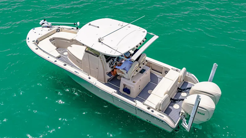 Slide: The Image of Aerial View of Helm and Deck This 2024 Grady-White 281 CE showcases a spacious helm area with advanced navigation controls, sheltered by a sleek T-top. The vessel's layout features ample seating and an open aft deck, perfect for fishing or leisure activities. Twin engines ensure powe - 7766853