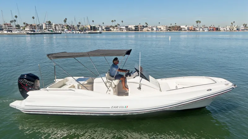 Slide: The Image of Side Profile of Zar Formenti 85 SL This image showcases the sleek side profile of the 2017 Zar Formenti 85 SL. The vessel features a spacious deck with comfortable seating and a practical helm station under a protective Bimini top. Its streamlined design, complemented by a powerful outboar - 7766836