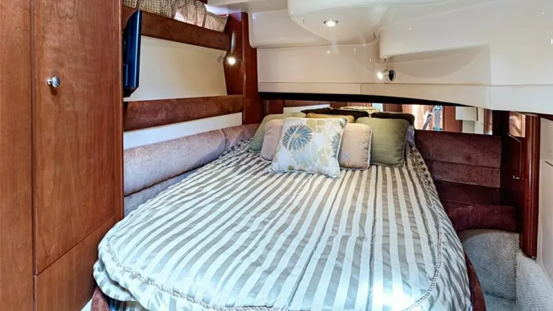Slide: The Image of Master Stateroom with Queen Bed This inviting master stateroom features a comfortable queen-sized bed adorned with elegant striped bedding and accent pillows. The warm wood cabinetry and soft lighting create a cozy and sophisticated ambiance. Ample storage options and a sleek wall-mount - 7766930