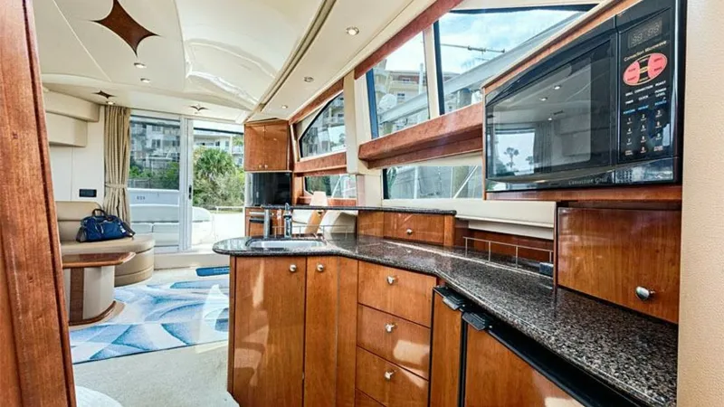 Slide: The Image of Galley and Salon with Panoramic Views The galley of the 2006 Meridian 391 Sedan features rich wood cabinetry and sleek granite countertops, offering ample storage and prep space. Large windows flood the area with natural light, providing stunning views and a sense of openness. Adjacent to the - 7766913