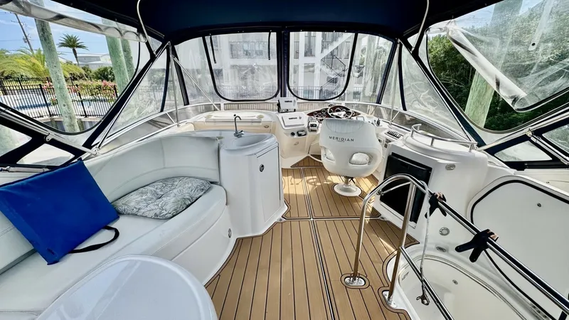Slide: The Image of Flybridge Helm and Seating Area This well-appointed flybridge of the 2006 Meridian 391 Sedan offers a comfortable helm station with excellent visibility. The area features a sleek, curved seating arrangement with plush cushions, complemented by a teak-style deck for added elegance. Encl - 7824270