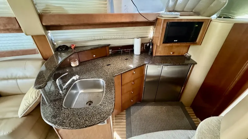 Slide: The Image of Galley with Granite Countertops This image showcases the galley of the 2006 Meridian 391 Sedan, featuring elegant granite countertops and well-crafted wood cabinetry. The space is equipped with modern appliances, including a built-in microwave and a stainless-steel sink, offering functi - 7824247