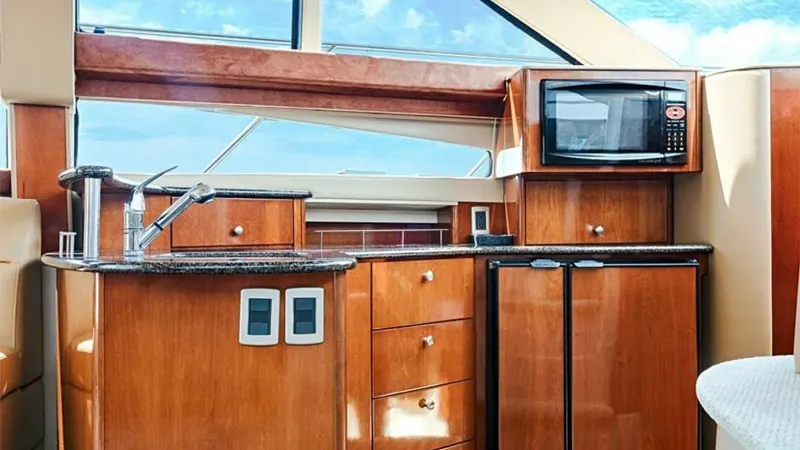Slide: The Image of Galley with Modern Amenities This elegant galley in the 2006 Meridian 391 Sedan features rich wood cabinetry and sleek granite countertops. Equipped with a built-in microwave and under-counter refrigerator, it offers both functionality and style. Large windows provide ample natural l - 7766922
