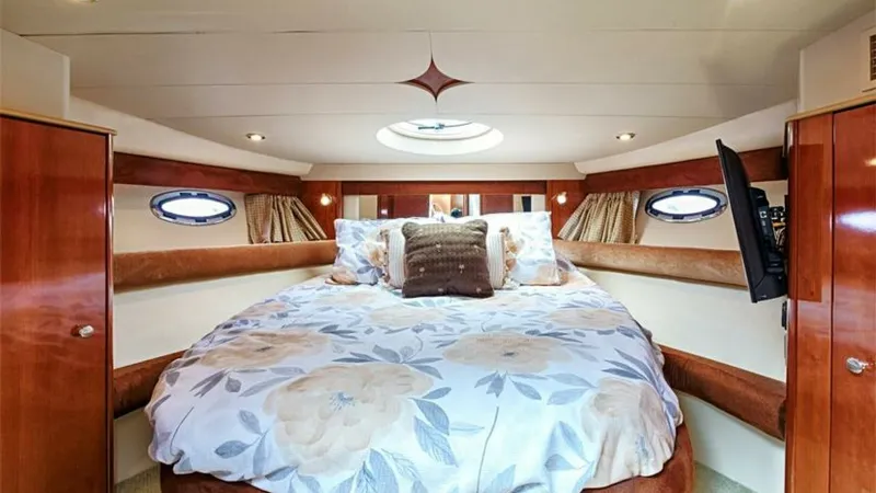 Slide: The Image of Luxurious Forward Stateroom with Skylight This forward stateroom on the 2006 Meridian 391 Sedan features a plush, centrally positioned double bed adorned with elegant bedding. The space is enhanced by natural light pouring in through a stylish overhead skylight and side portholes, creating an inv - 7766926