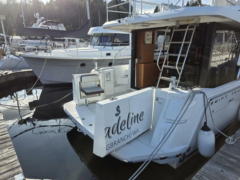 Slide: The Image of 2020 Beneteau Swift Trawler 30 docked at marina, rear view with ladder and seating - 7818221
