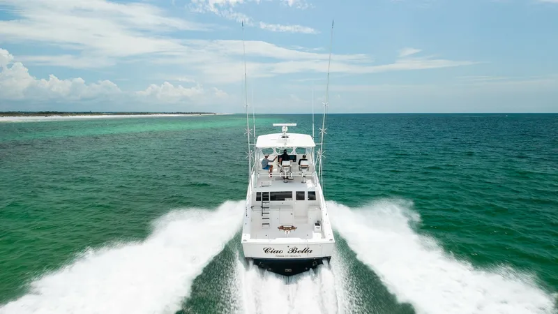 Slide: The Image of Aerial View of Aft Deck Underway The Cabo 43 Convertible 'Chao Bella' is captured in motion, showcasing its powerful performance on open waters. The aft deck features a spacious, open layout ideal for fishing and leisure, with a clean white finish accentuating its sleek design. The vesse - 7831821