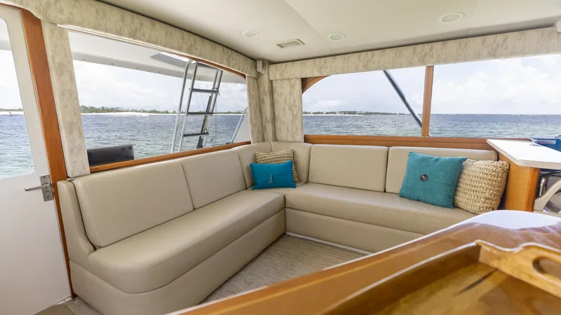 Slide: The Image of Spacious Interior Salon with Ocean Views This inviting interior salon on the 2003 Cabo 43 Convertible features a plush L-shaped seating area, perfect for relaxation or entertaining guests. Large windows provide stunning panoramic ocean views, enhancing the bright and airy atmosphere. The space i - 7831789