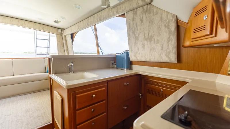 Slide: The Image of Galley with Ample Counter Space This well-appointed galley on the 2003 Cabo 43 Convertible features sleek countertops and rich wood cabinetry, offering both style and functionality. The layout provides plenty of storage and workspace, ideal for meal preparation while at sea. Large windo - 7831795