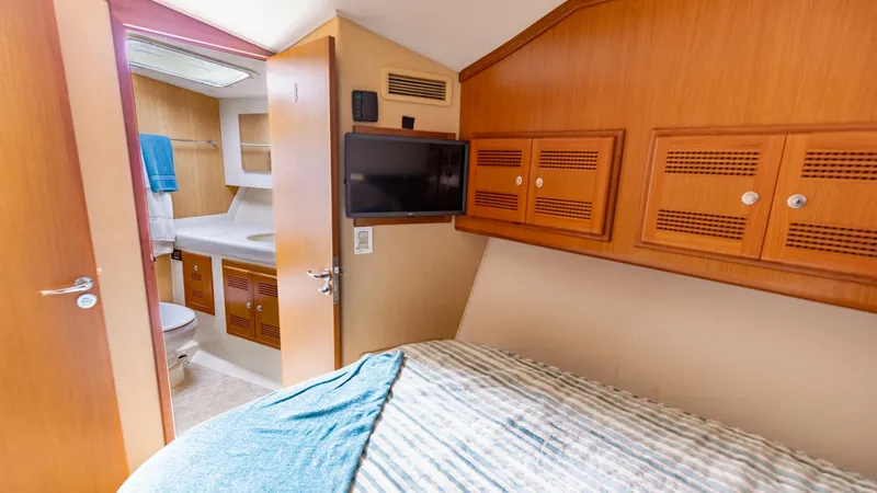 Slide: The Image of Guest Cabin with En Suite This cozy guest cabin on the 2003 Cabo 43 Convertible features a comfortable berth with elegant wood cabinetry for ample storage. The cabin offers direct access to a private en suite bathroom, equipped with modern fixtures and a spacious shower. Natural l - 7831799