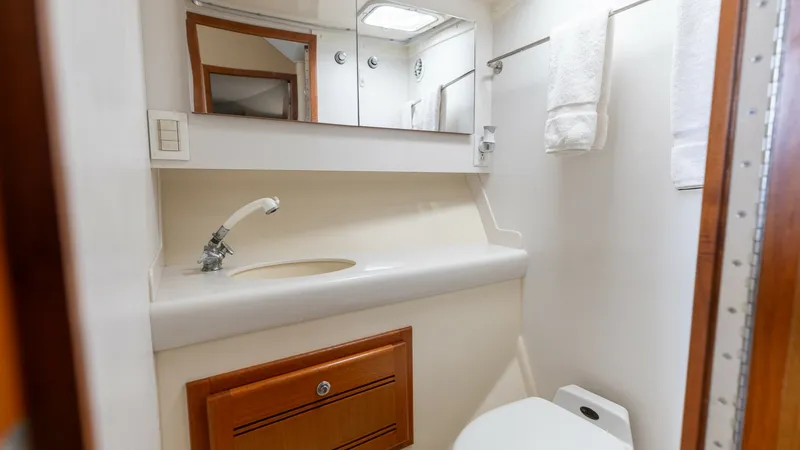 Slide: The Image of Compact Yacht Bathroom Interior This well-appointed yacht bathroom features a sleek vanity with an integrated sink and a modern faucet, offering both style and functionality. The mirrored cabinet above provides ample storage, while the polished wood accents add a touch of elegance. The - 7831803