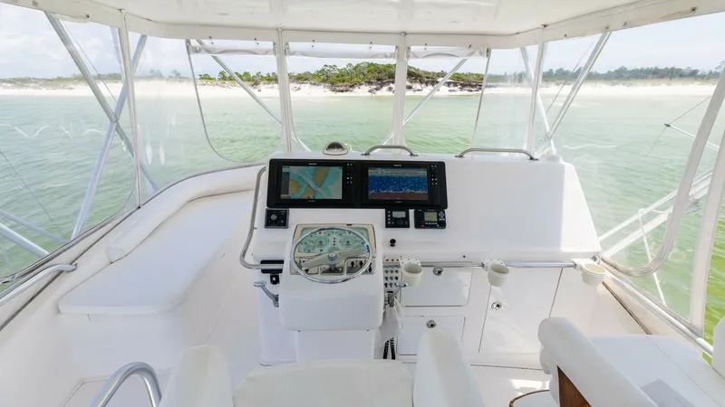 Slide: The Image of Flybridge Helm Station The flybridge helm station of the 2003 Cabo 43 Convertible offers a commanding view, equipped with state-of-the-art navigation systems for precise control. The seating area is designed for comfort, with plush chairs and ample space for maneuvering. The ex - 7831804