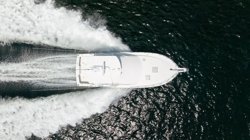 Slide: The Image of Aerial View of Yacht Underway This striking aerial shot showcases the Cabo 43 Convertible, 'Chao Bella,' gracefully cutting through the water. The sleek hull and dynamic wake highlight the vessel's powerful performance and agility. The clean, streamlined design emphasizes both luxury - 7831823