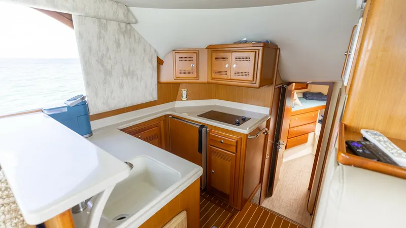 Slide: The Image of Galley with Modern Amenities This well-appointed galley on the 2003 Cabo 43 Convertible features sleek countertops and ample storage with custom cabinetry. The compact layout includes a built-in sink and modern appliances, ideal for meal preparation while enjoying the views through t - 7831792