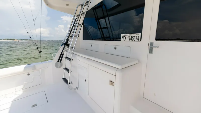 Slide: The Image of Cockpit with Ladder Access This image showcases the spacious cockpit area of the 2003 Cabo 43 Convertible, featuring a sturdy ladder leading to the flybridge. The clean, white surfaces and practical storage cabinets enhance functionality, making it ideal for both leisure and sport - 7831814