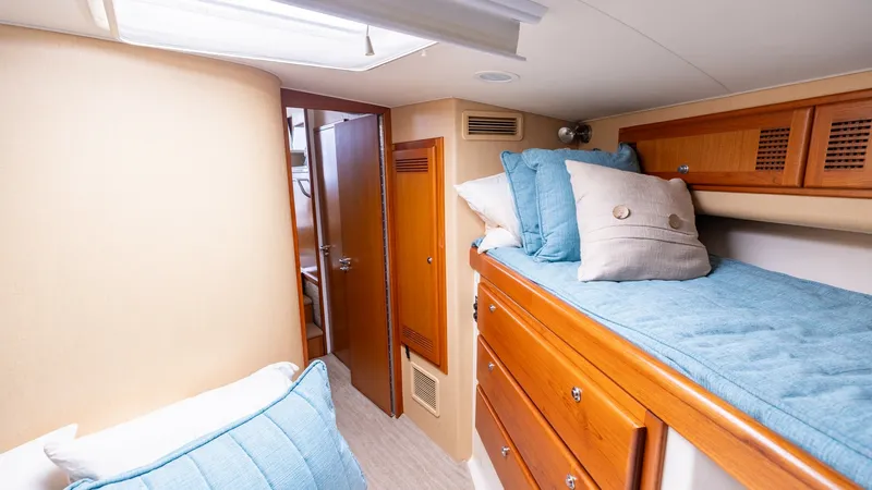 Slide: The Image of Guest Cabin with Bunk Beds This inviting guest cabin features comfortable bunk beds with plush blue cushions, providing a cozy retreat. The warm wood cabinetry offers ample storage, complemented by soft beige walls and a skylight that brightens the space. Ideal for relaxation, this - 7831801