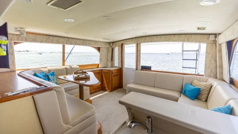 Slide: The Image of Spacious Interior Salon with Panoramic Views The salon of the 2003 Cabo 43 Convertible features an inviting, open layout with expansive windows offering panoramic ocean views. Plush seating with tasteful upholstery complements the warm wood finishes, creating a welcoming atmosphere. A stylish dinett - 7831785