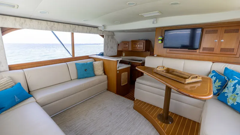 Slide: The Image of Spacious Interior Salon with Ocean View The interior salon of the 2003 Cabo 43 Convertible offers a comfortable and stylish retreat. Plush cream-colored seating is accented with vibrant blue cushions, providing a welcoming atmosphere. Large windows allow natural light to flood the space, highli - 7831782