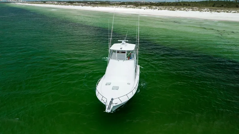 Slide: The Image of Aerial Bow View in Open Water This aerial shot showcases the sleek bow of the 2003 Cabo 43 Convertible, 'Chao Bella,' as it glides through vibrant green waters. The well-maintained deck features a clean, streamlined design, perfect for navigating coastal adventures. The vessel's sturd - 7831818
