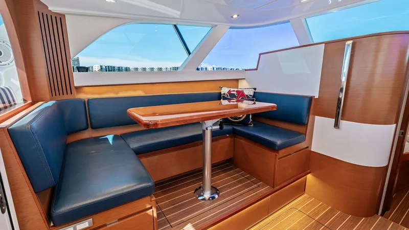 Slide: The Image of Flybridge Dinette Area This inviting flybridge dinette area on the 2019 Bertram 35 features a sleek, modern design with comfortable navy blue seating and a polished wooden table. The ample natural light from the large windows enhances the bright and airy atmosphere, making it a - 7851520