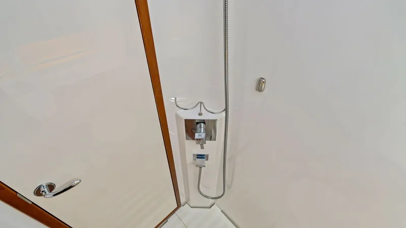Slide: The Image of Compact Yacht Shower Area The shower area of the 2019 Bertram 35 Flybridge features sleek, modern fixtures and a clean, minimalist design. The space is efficiently utilized, offering a practical and comfortable environment with high-quality materials and a streamlined aesthetic. E - 7851533