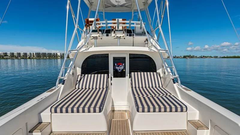 Slide: The Image of Aft Deck with Sun Loungers This aft deck on the 2019 Bertram 35 Flybridge features luxurious striped sun loungers, perfect for relaxation. The teak decking adds elegance and durability, complementing the vessel's sleek design. Overhead, the flybridge provides shade and protection, - 7851518
