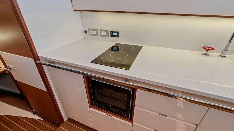 Slide: The Image of Modern Galley with Cooktop The galley of the 2019 Bertram 35 Flybridge features a sleek, modern design with a smooth white countertop and integrated cooktop. Ample storage is provided by the cabinetry below, complemented by a high-end oven. The efficient layout and contemporary fin - 7851522