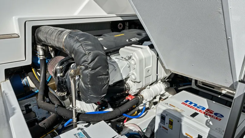 Slide: The Image of Engine Room with Generator View This image showcases the well-organized engine room of the Bertram 35 Flybridge, featuring a powerful diesel engine. The layout is clean and efficient, providing easy access for maintenance and inspection. Notably, the Mase generator is prominently positi - 7851550