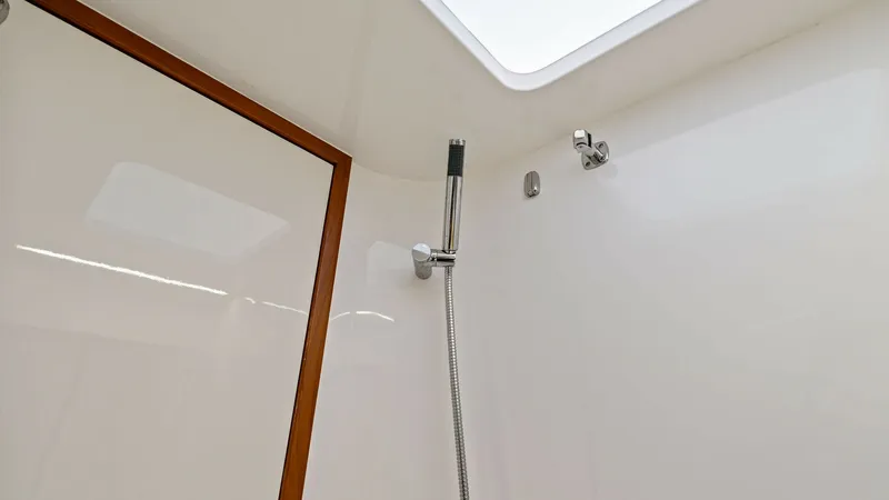 Slide: The Image of Spacious Shower with Skylight This image showcases the sleek shower area of the 2019 Bertram 35 Flybridge. The space features a contemporary design with a high-quality handheld shower fixture and elegant wood trim accents. A skylight above floods the area with natural light, enhancing - 7851532