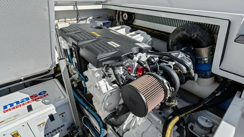 Slide: The Image of Engine Room with Diesel Engine The engine room of the 2019 Bertram 35 Flybridge showcases a powerful diesel engine, ensuring reliable performance on the water. The space is well-organized, with easy access to the engine components and a Mase generator, enhancing operational efficiency. - 7851548