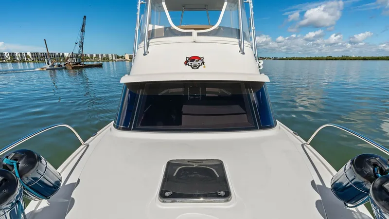 Slide: The Image of Flybridge and Foredeck View This image showcases the sleek foredeck and commanding flybridge of the 2019 Bertram 35 Flybridge. The spacious foredeck features a central hatch, providing access to below-deck areas, surrounded by polished stainless steel rails for safety. Above, the fl - 7851543