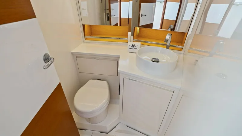 Slide: The Image of Elegant Onboard Bathroom The bathroom on the Bertram 35 Flybridge features sleek, modern fixtures and a compact yet functional layout. It includes a stylish vessel sink and mirrored cabinets, offering ample storage and a bright, inviting atmosphere. The high-quality finishes and - 7851530