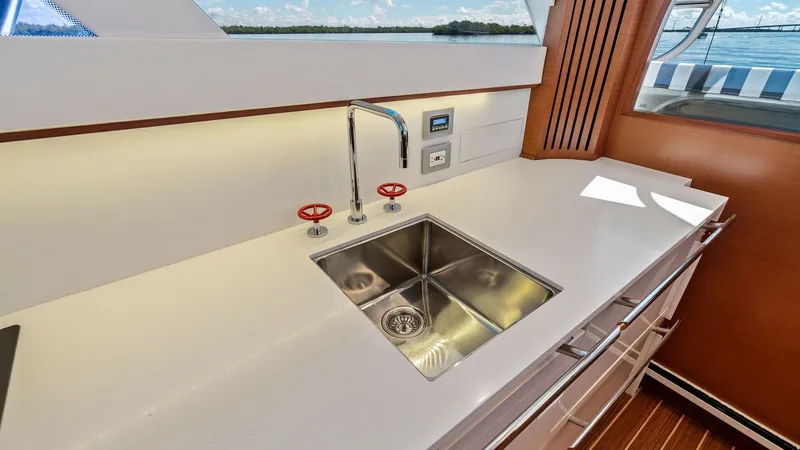 Slide: The Image of Galley with Stainless Steel Sink The galley of the 2019 Bertram 35 Flybridge features a sleek stainless steel sink set into a pristine white countertop. Elegant cabinetry provides ample storage, while the contemporary faucet and fittings add a touch of sophistication. Large windows offer - 7851523
