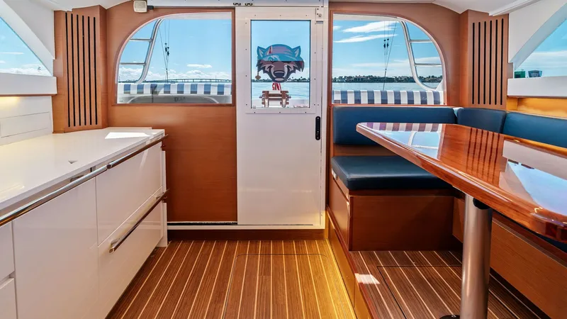 Slide: The Image of Flybridge Interior with Dining Area This elegant flybridge interior features a sleek dining area with a polished wooden table and comfortable upholstered seating. The surrounding cabinetry offers ample storage, finished in a crisp white that complements the warm wood tones of the flooring. - 7851519