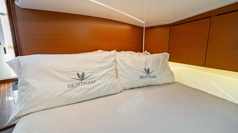 Slide: The Image of Guest Cabin with Plush Bedding This inviting guest cabin on the 2019 Bertram 35 Flybridge features plush bedding and elegant wood paneling, creating a warm and comfortable atmosphere. The soft lighting enhances the cozy feel, while ample storage space is cleverly integrated into the de - 7851528