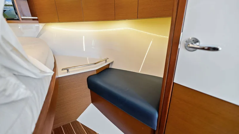 Slide: The Image of Master Stateroom Seating Area This cozy seating area in the master stateroom of the 2019 Bertram 35 Flybridge offers a comfortable place to relax. The space is elegantly designed with warm wood finishes and soft ambient lighting. The leather seating and sleek cabinetry provide both st - 7851529