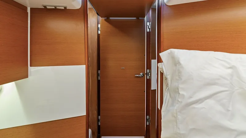 Slide: The Image of Cabin Interior with Doorway View This image showcases the warm and inviting interior of the Bertram 35 Flybridge, featuring rich wood paneling and modern finishes. A doorway leads to additional spaces, enhancing the functional layout of the cabin. The soft lighting and comfortable beddin - 7851527