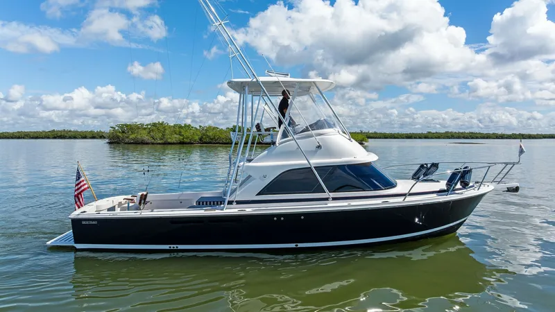 The Image of Starboard View of Flybridge Cruiser This image showcases the sleek starboard side of the 2019 Bertram 35 Flybridge, Loco Lobo Del Mar II. The vessel's sophisticated black hull contrasts elegantly with the bright, open flybridge, offering panoramic views and excellent visibility for navigati - 7851505
