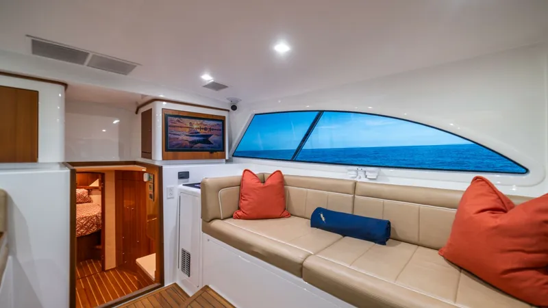 Slide: The Image of Salon Lounge with Ocean View The salon of the Viking 46 BF features a plush seating area with elegant tan upholstery and vibrant accent cushions, offering a comfortable space to relax. A large, stylishly curved window provides a stunning ocean view, enhancing the sense of openness an - 7854749