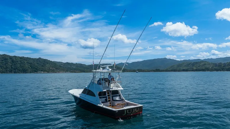 Slide: The Image of Aerial Stern View with Tower This image showcases the elegant stern of the 2020 Viking 46 BF, named JUJU, as it glides through serene waters. The vessel features a spacious cockpit with ample seating and rod holders, ideal for fishing enthusiasts. Its sleek lines and elevated tower p - 7854778