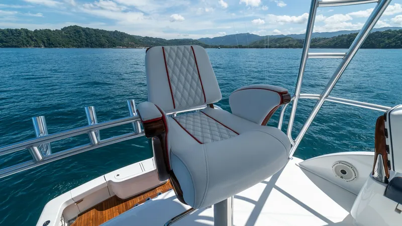 Slide: The Image of Flybridge Helm Seating Area This image showcases the luxurious helm seating area on the flybridge of the Viking 46 BF, JUJU. The seat features elegant diamond-stitched upholstery with accent piping, providing both comfort and style. The surrounding panoramic views enhance the cruisi - 7854767
