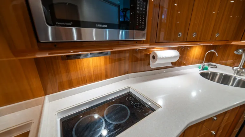 Slide: The Image of Galley with Modern Appliances The galley of the Viking 46 BF showcases a sleek, modern design with high-gloss cabinetry and polished countertops. Equipped with a built-in microwave and a two-burner cooktop, the space is both functional and stylish. The stainless steel sink and ample s - 7854753