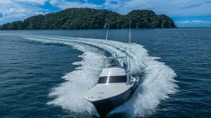 Slide: The Image of Viking 46 BF Aerial Bow View This dynamic aerial shot showcases the sleek bow of the 2020 Viking 46 BF, cutting effortlessly through the water. The vessel's elegant design and sturdy construction are evident as it creates a striking wake against a backdrop of lush, green islands. Thi - 7854784