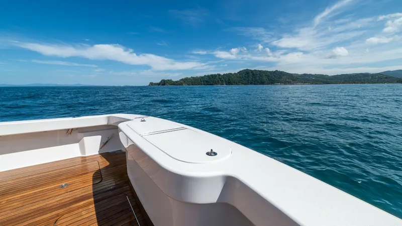 Slide: The Image of Sleek Aft Deck with Ocean View The aft deck of the 2020 Viking 46 BF 'JUJU' showcases a beautifully finished teak flooring, offering a spacious area for leisure and fishing. The clean lines of the white gunwale complement the expansive ocean views, creating an inviting space for relaxa - 7854763